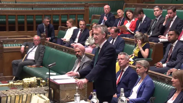 Dan Jarvis stands in the House of Commons, with MPs sitting behind him on the green benches.