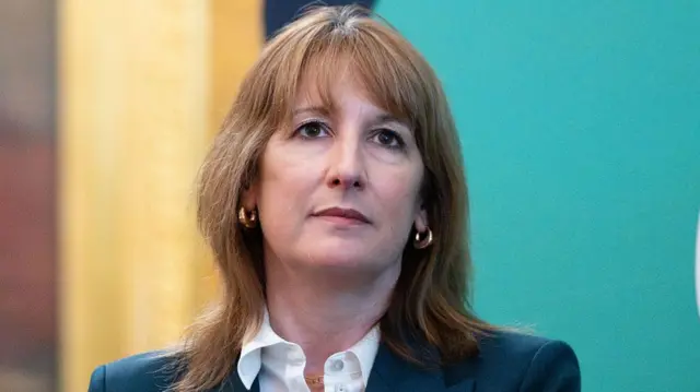 Chancellor Rachel Reeves looks ahead while wearing a dark coloured blazer and a white blouse.