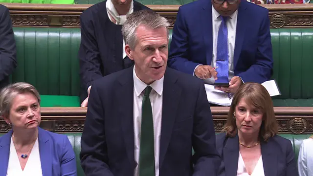 Dan Jarvis speaks in the House of Commons, wearing a dark suit and a green tie. Rachel Reeves can be seen sitting to the right.