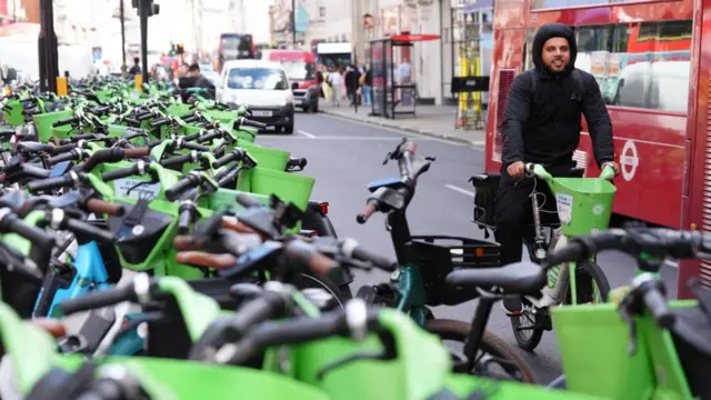 A man on a Lime Bike rides past hundreds of other hire bikes