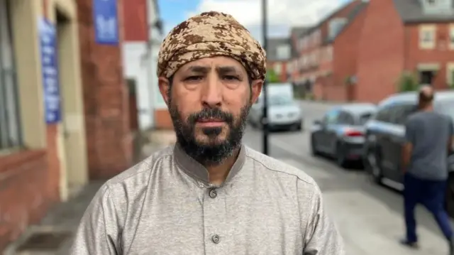A man wearing traditional clothes looks straight into the camera