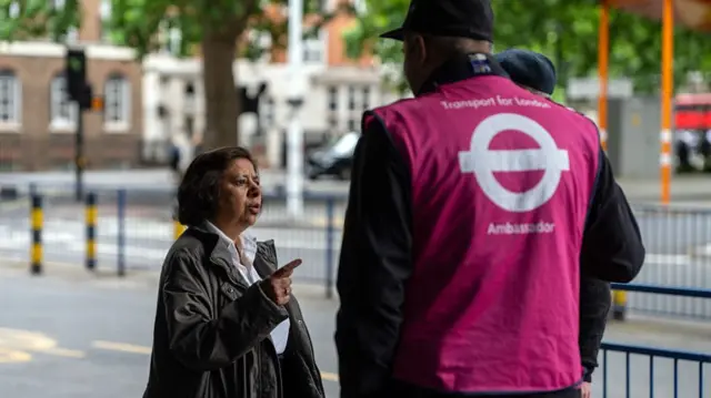 A commuter talks with Transport for London assistance staff at Euston Station