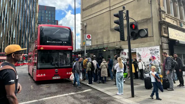 Several people queing to get on a bus