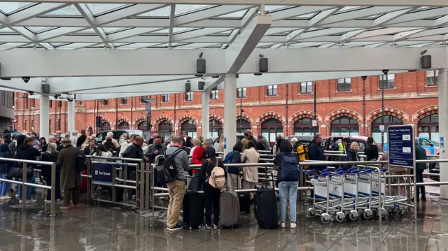 People queue outside King's Cross station near to the taxi rank