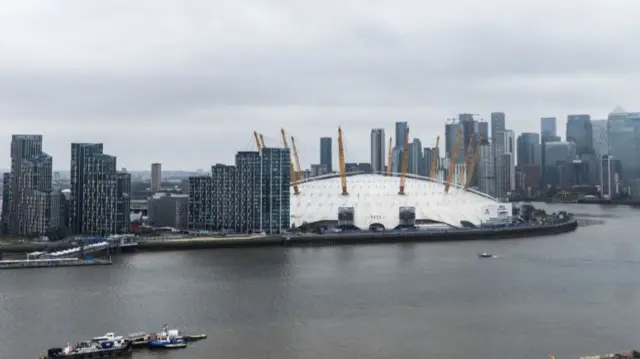 A view of the O2 which is a big white dome in the middle of the river surrounded by skyscrapers
