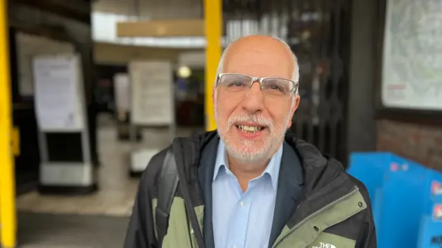 White bearded and bespectacled man smiles at camera