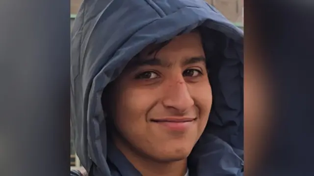 Close-up of a young boy wearing a blue coat with the hood up