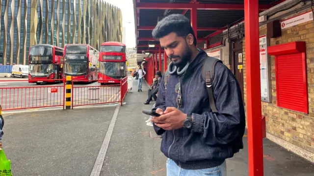 A man looking at his phone at a bus station