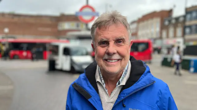 Man in blue jacket with moustache smiles