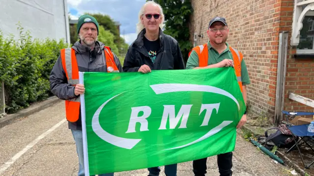 Three men hold RMT flag