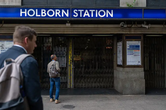 Two men wait look on outside Holborn Station in London where the barriers are closed due to tube strikes