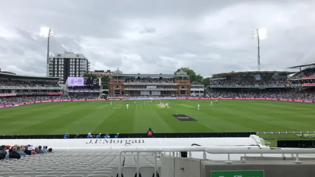Lord's cricket ground shows grass and pavilion and cricketers