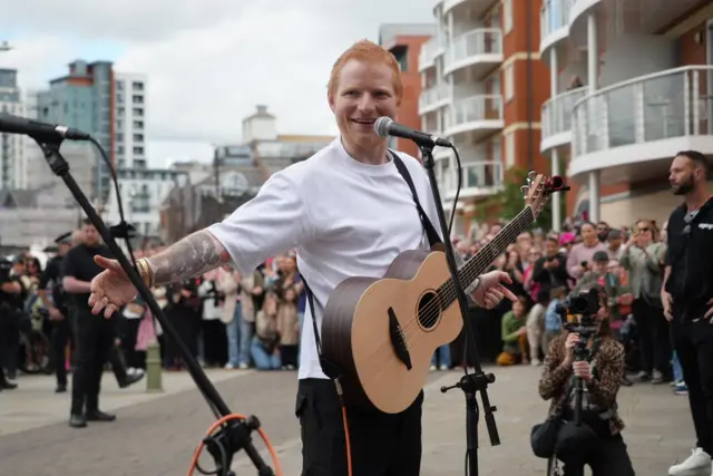 Ed holding his hand out to the stand up mic and singing to the crowd