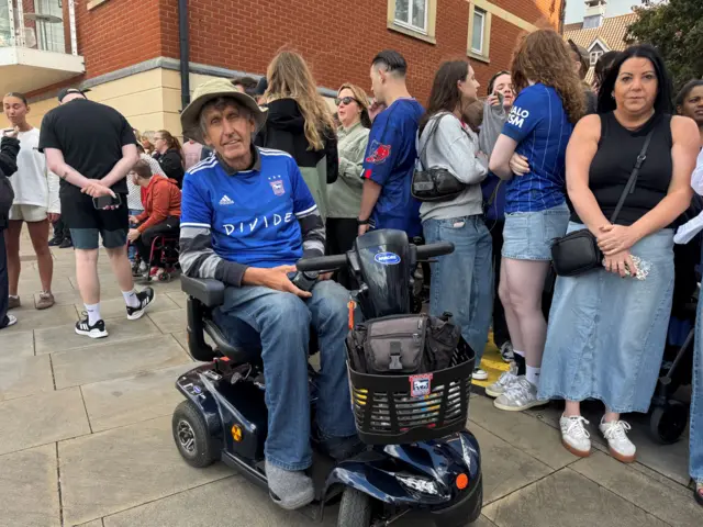 A man in a mobility scooter smiling at the camera