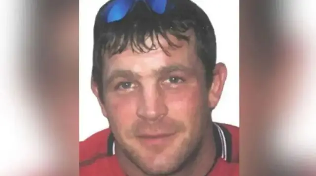 Paul Quinn is shown in a historical police handout image, wearing a red top with sunglasses on the top of his head.