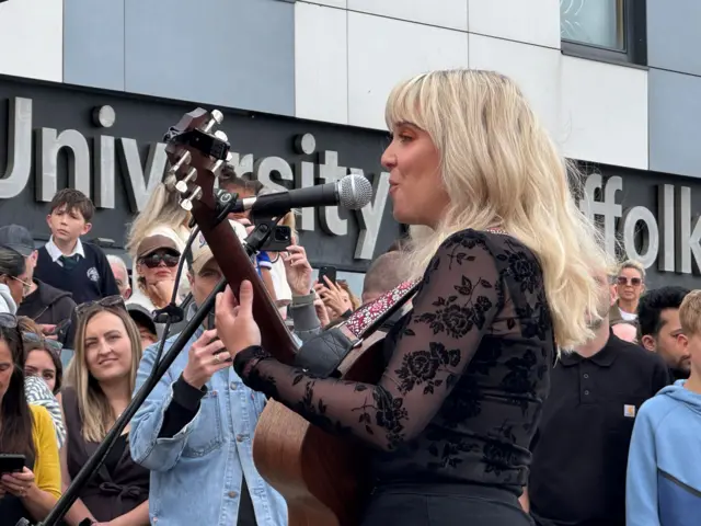 A singer wearing all black playing the guitar