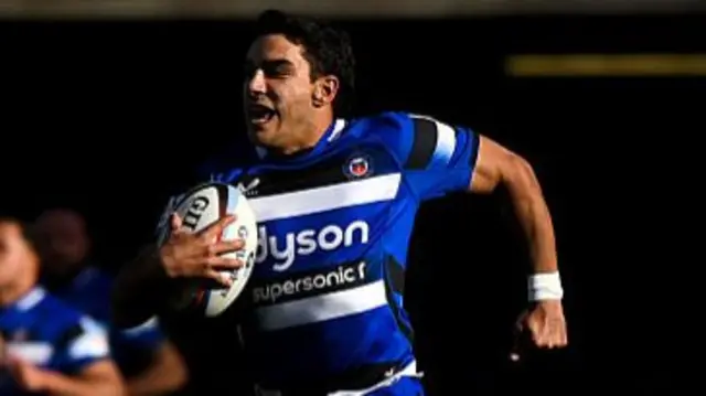 Bath's Santi Carreras smiling while heading towards the try line, ball in hand.