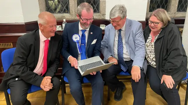Four people sat looking at a laptop
