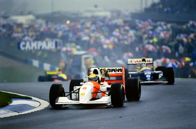 McLaren's Ayrton Senna waves a Brazilian flag in celebration in front of Damon Hill during the European GP at Donington Park in 1993