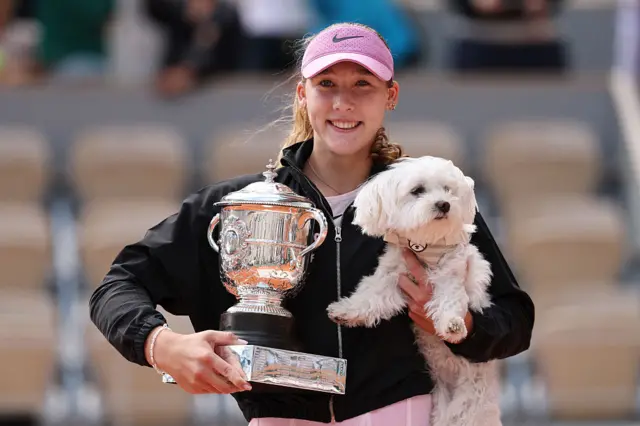 Mirra Andreeva poses for a photo with the Coupe Suzanne Lenglen winners trophy whilst holding her dog