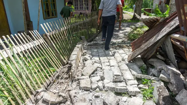 People walking past a damaged pavement