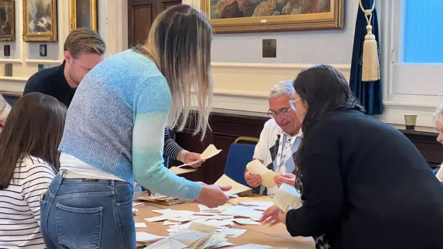 People count votes on a table for the 2026 Jersey general election
