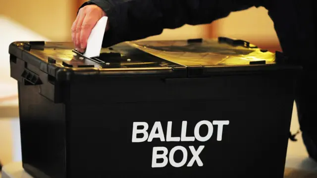 A voter placing a ballot paper in a ballot box at a polling station