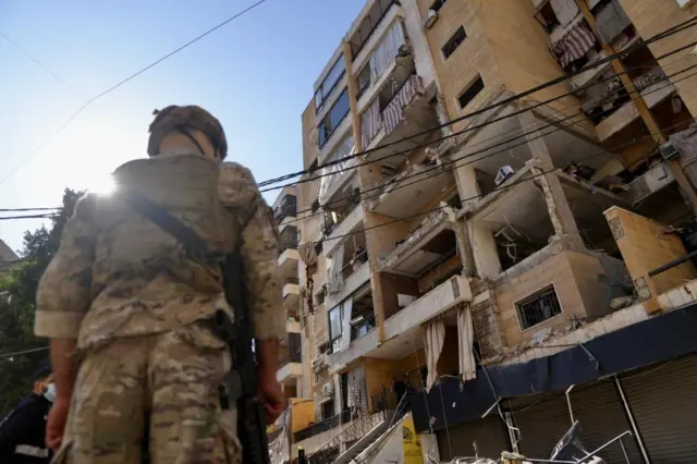 An soldier stands at the site of an Israeli air strike on an apartment in the southern suburbs of Beirut on Sunday