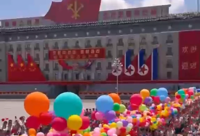 A crowd with balloons welcoming Xi