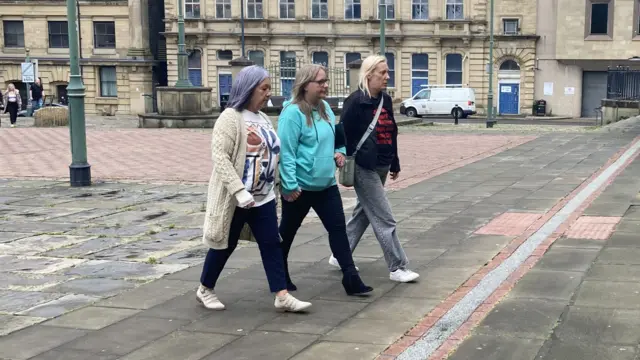 Three women walk hand-in-hand into court.