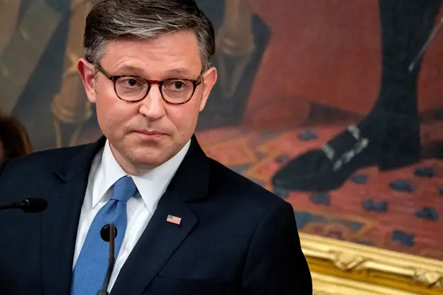 Speaker of the House Mike Johnson wearing glasses, a suit and a blue tie