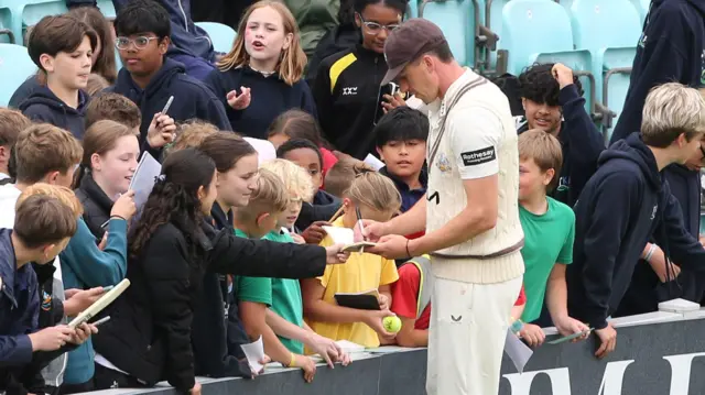 Matt Fisher signs autographs for children after his two wickets on day two