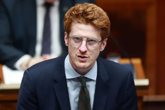 Matthew O'toole in assemby chamber, blue suit, red hair.