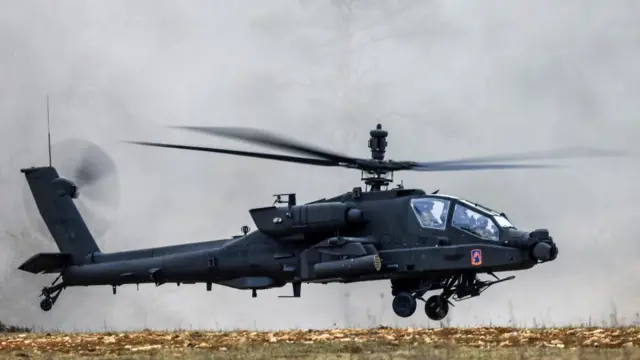 A US Army Apache helicopter hovering just off the ground in March 2025 in Germany