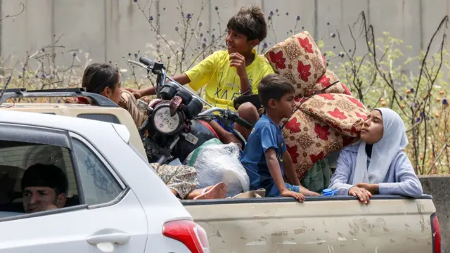 Children sit in the bed of a pickup truck waiting in traffic in Tyre, southern Lebanon