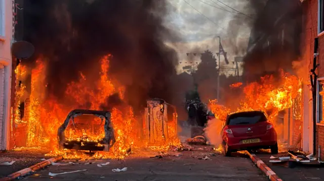 Vehicles set on fire by protesters on Lendrick Street in Belfast.