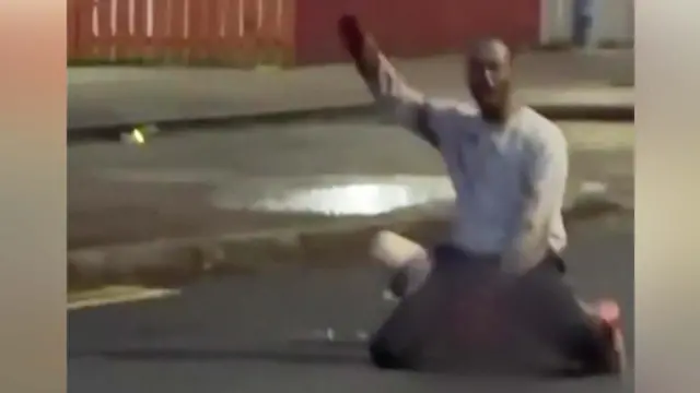 The suspected attacked kneeling over the injured man - the still is from a social media video and is low resolution