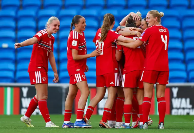 Wales players celebrate Gemma Evans (hidden) scoring a goal