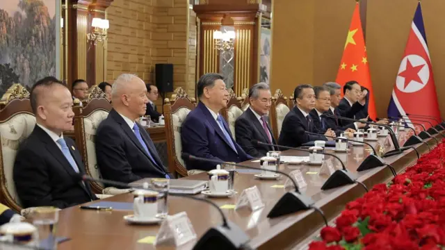 Xi Jinping sitting in a row with his delegation at a long table