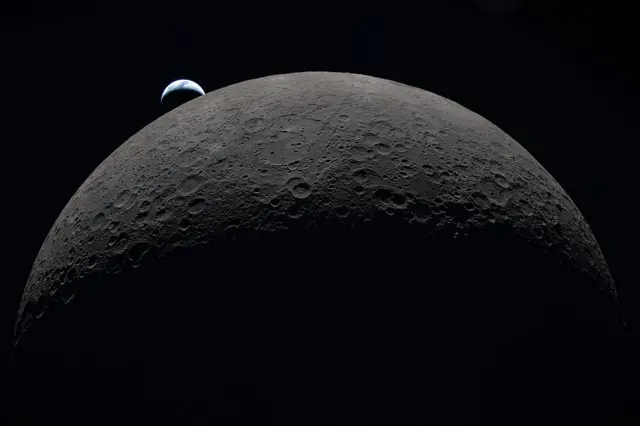 In this handout image provided by NASA, Earth sets at 6:41 p.m. EDT, April 6, 2026, over the Moon’s curved limb in this photo captured by the Artemis II crew during their journey around the far side of the Moon.