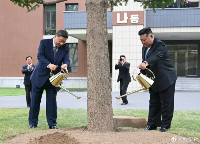Xi and Kim holding watering cans