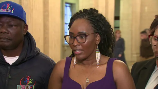 Lilian Seenoi-Barr standing in the great hall at Stormont speaking to reporters