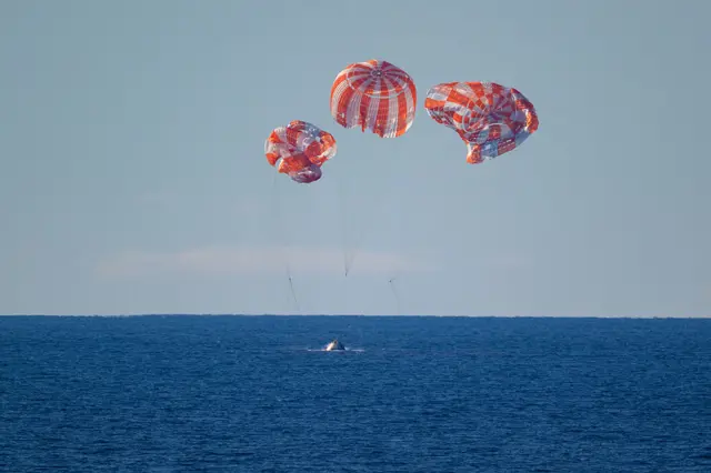 NASA's Orion spacecraft with Artemis II crewmembers NASA astronauts Reid Wiseman, commander; Victor Glover, pilot; Christina Koch, mission specialist; and CSA (Canadian Space Agency) astronaut Jeremy Hansen, mission specialist aboard is seen as it lands in the Pacific Ocean off the coast of California.