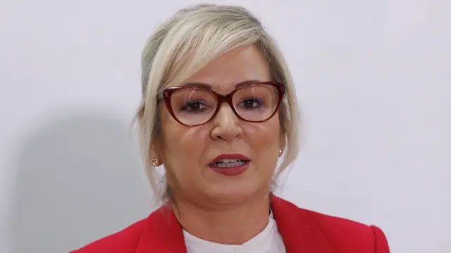 A woman with blonde hair and red glasses