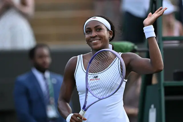 Coco Gauff holds up her hand and is holding a tennis racquet