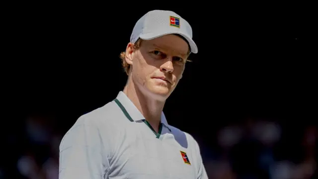 Jannik Sinner, wearing a white polo shirt and cap
