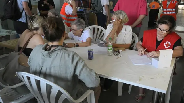People sitting at a white table across from health officials who write on paper