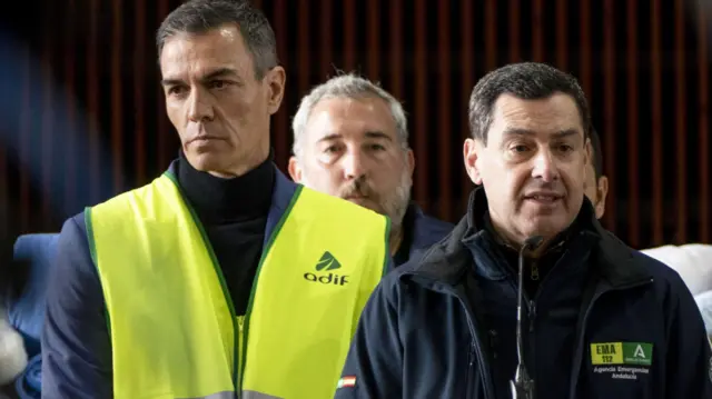 Spain's Prime Minister Pedro Sanchez (L), and Andalusian regional President Juanma Moreno (R) address the media during their visit to the site of a major train collision near the town of Adamuz, Cordoba province, southern Spain, 19 January 2026