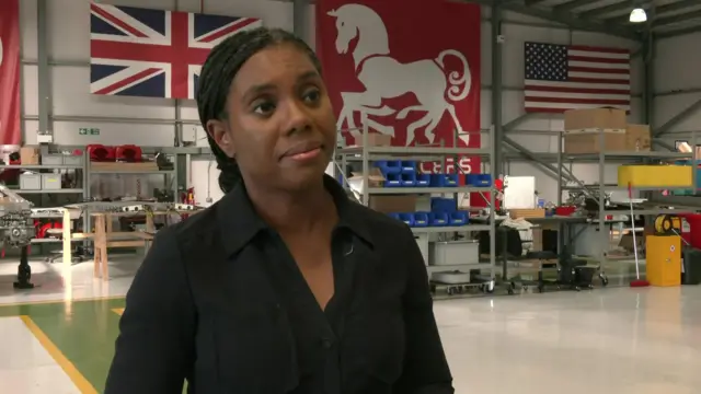 Kemi Badenoch, a woman wearing black, inside a factory.