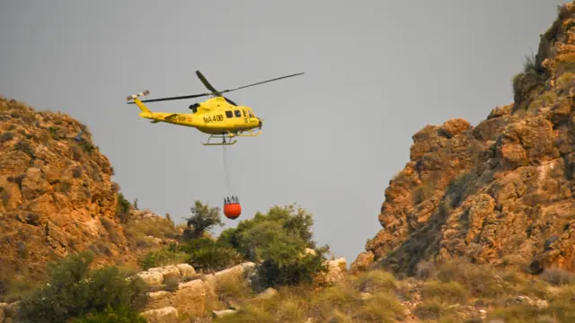 An helicopter carries water to battle the flame of a wildfire in Los Gallardos, province of Almeria, southwestern Spain, 10 July 2026